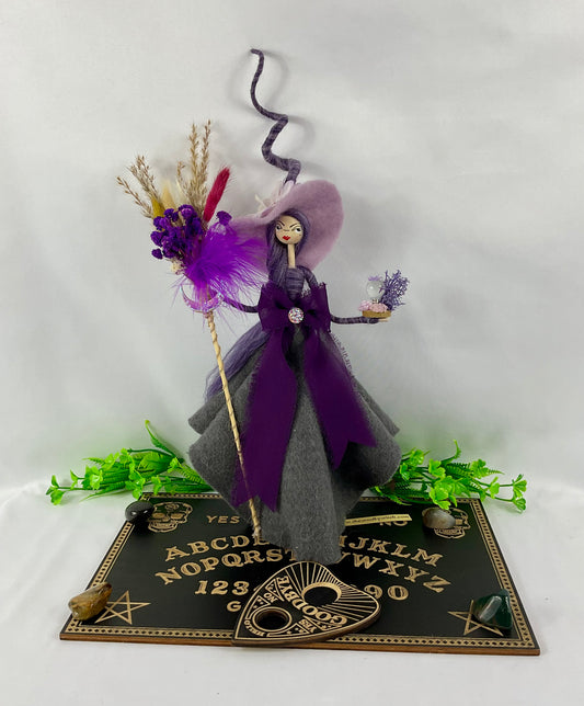 Purple witch with ouija board display and tumble stones
